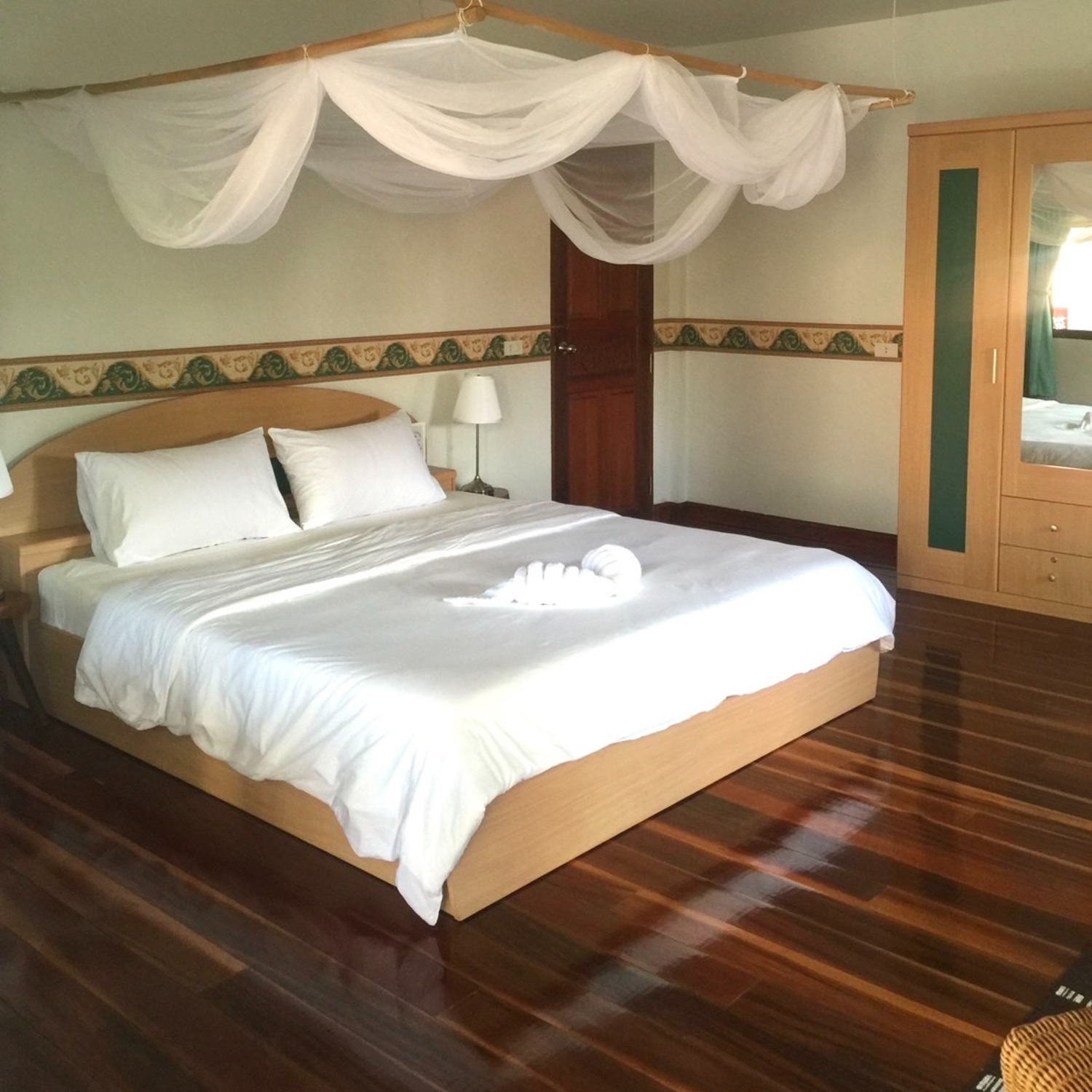 Superior Room at Lyndale Lodge with a draped mosquito-net canopy bed and rich timber flooring